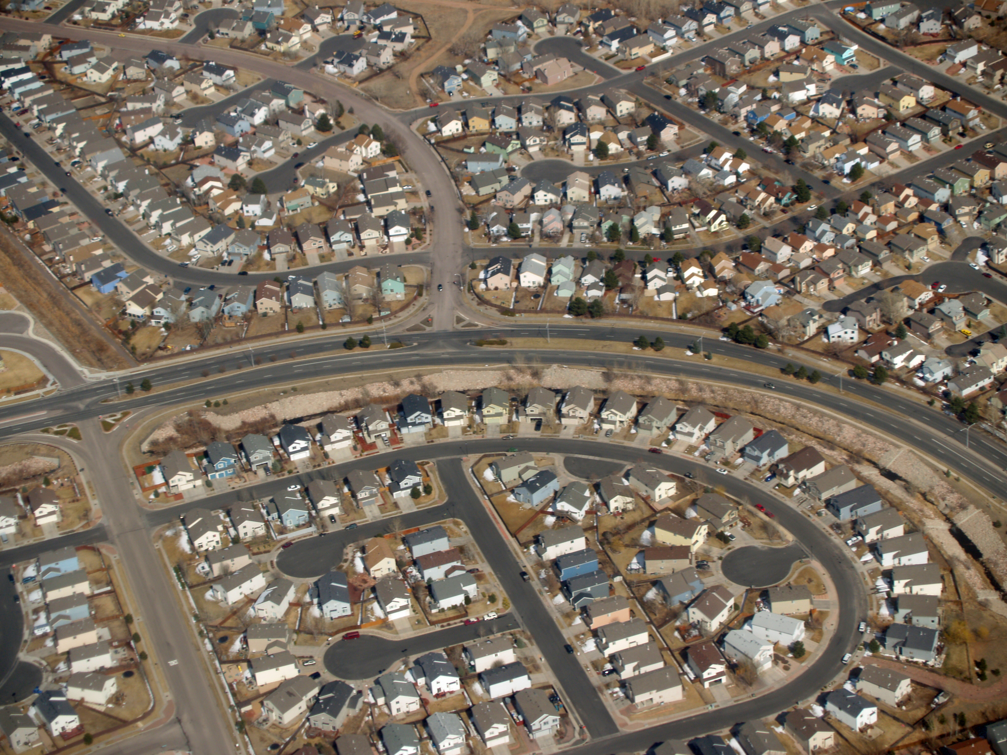 Sprawling suburban development with curved roads, multiple cul-de-sacs, and little vegetation