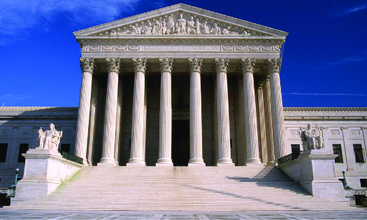 An image of the Supreme Court building. In the foreground, a set of stairs is bracketed by statues on either side, leading up