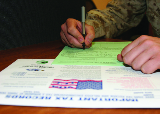 An image of a person's hand, holding a pen over a form.