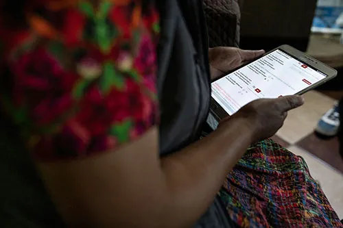 A person holds a tablet in their lap. The screen shows a survey.