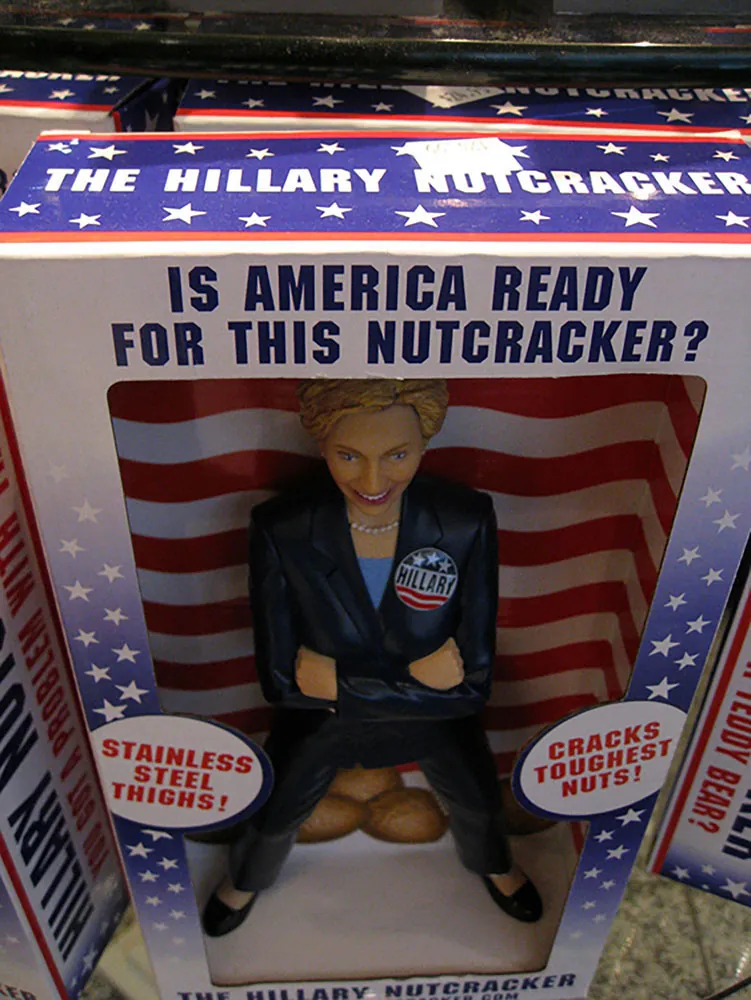 A toy figure of Hilary Clinton is shown in a packaging box reading "Is America Ready for This Nutcracker?"