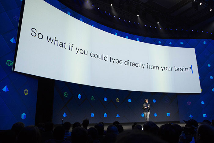 Facebook VP of Engineering Regina Dugan stands on a stage with a large screen above her.