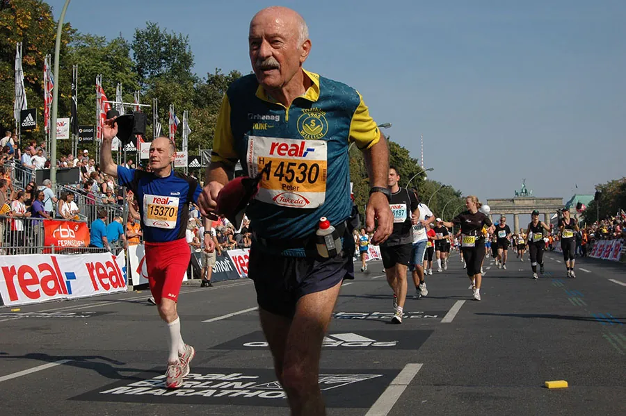 A group of people run a marathon in Berlin, Germany. The Brandenberg Gate is in the background. In the immediate foreground a