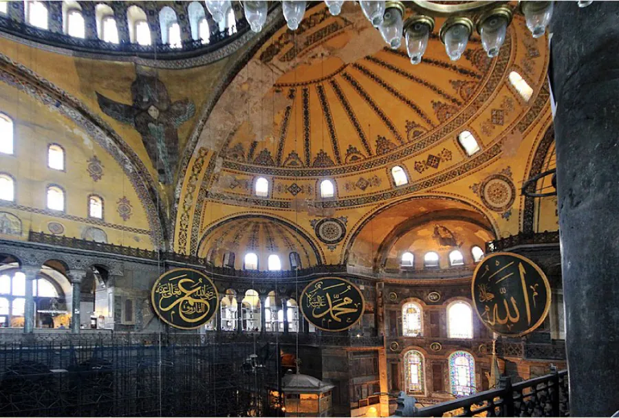  This photograph shows the interior of Hagia Sophia. The building has richly decorated dome ceilings. Medallions bearing Arab