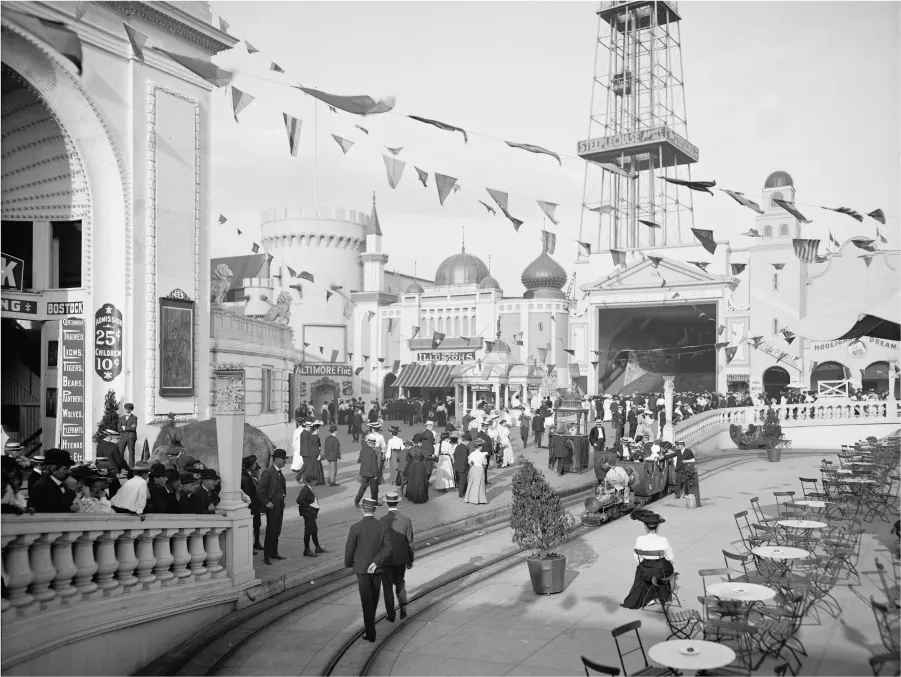 This photograph shows a crowd of people visiting the Dreamland amusement park. All the men are wearing suits and hats. The wo