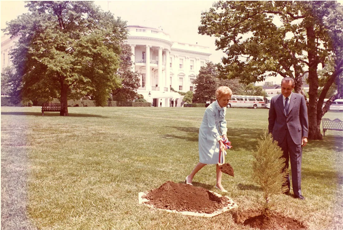 A photo is shown of a lawn, trees, and a large white building with a rounded front in the background. In the right forefront 